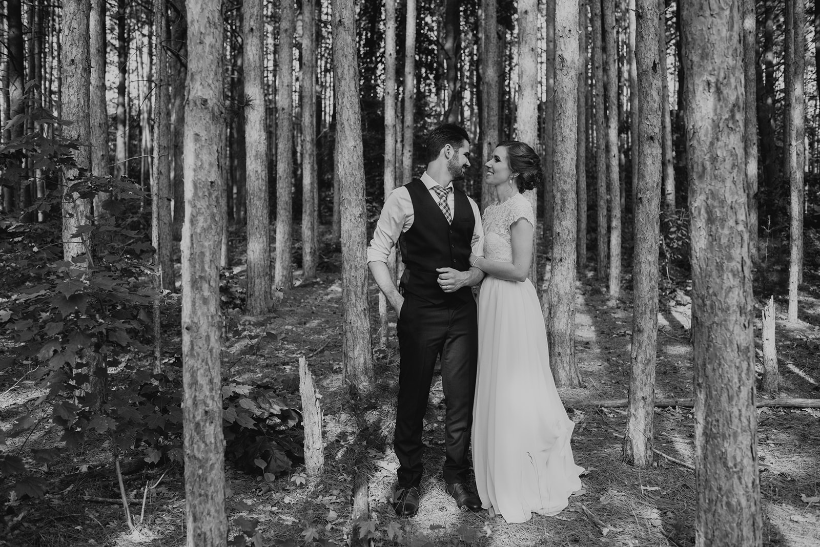 Two MArriers on in a wedding dress from Bianka Bridal in the woods with tall pines 