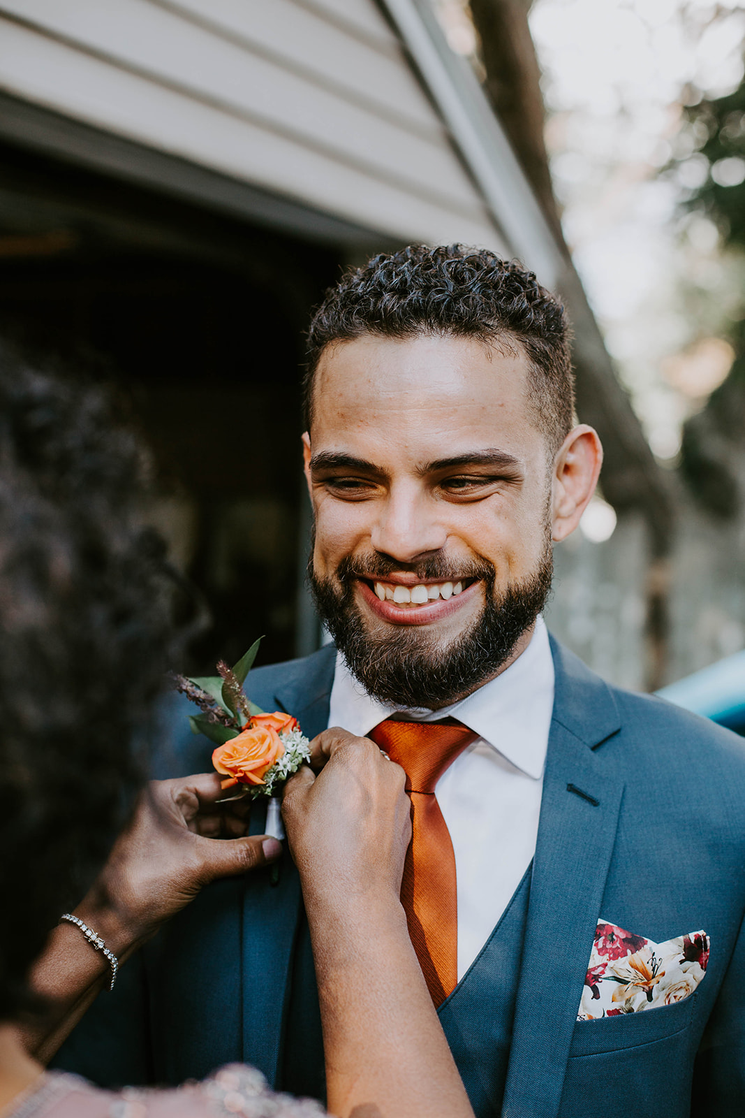 Groom smiling. Orange and white boutonniere. Outdoor wedding. Orange, green and white flowers. intimate wedding photography. michigan photographer. 