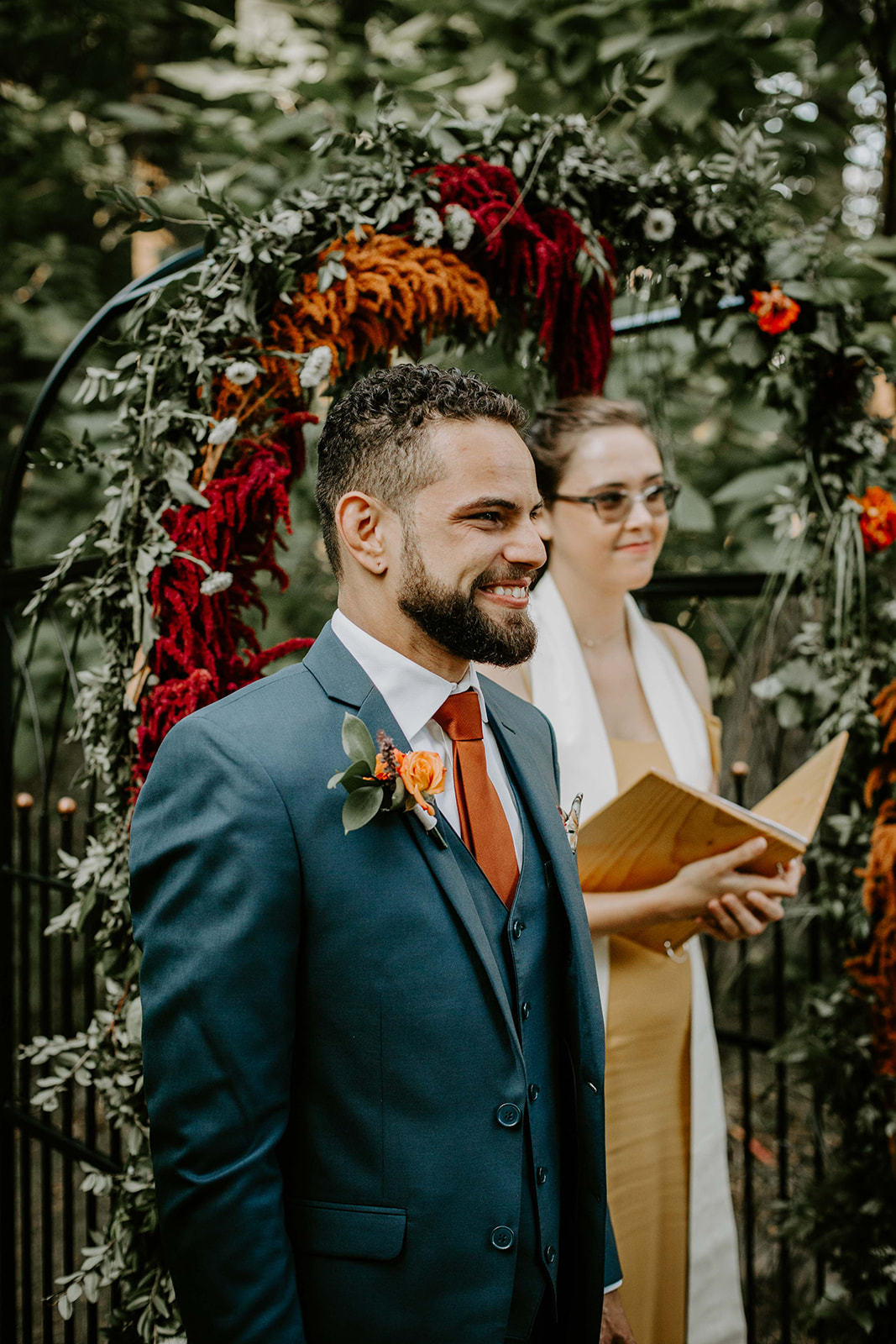 Groom at altar. Orange, red and white flower. Outdoor wedding. intimate wedding photography. michigan photographer. 
