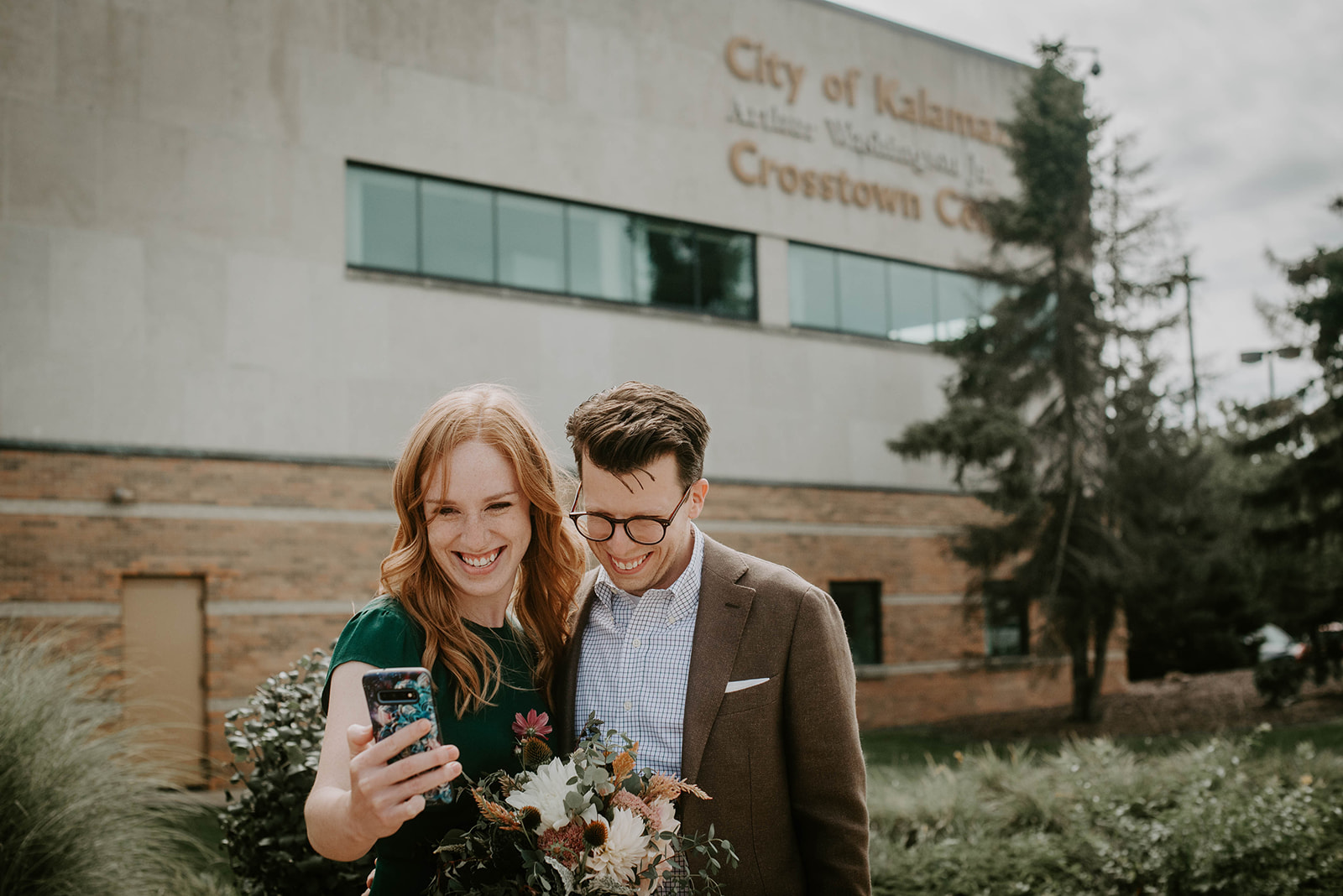 Bride and groom on phone in front of courthouse. Kalamazoo, mi. Elopement Photographer