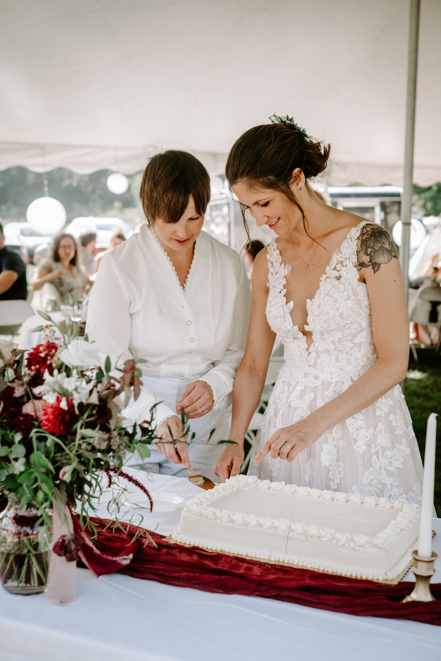 Two brides cutting a cake from Bert's bakery in Kalamazoo Michigan photographed by Liv Lyszyk photography queer inclusive photographer in Michigan tented receptions in Michigan Michigan tent wedding