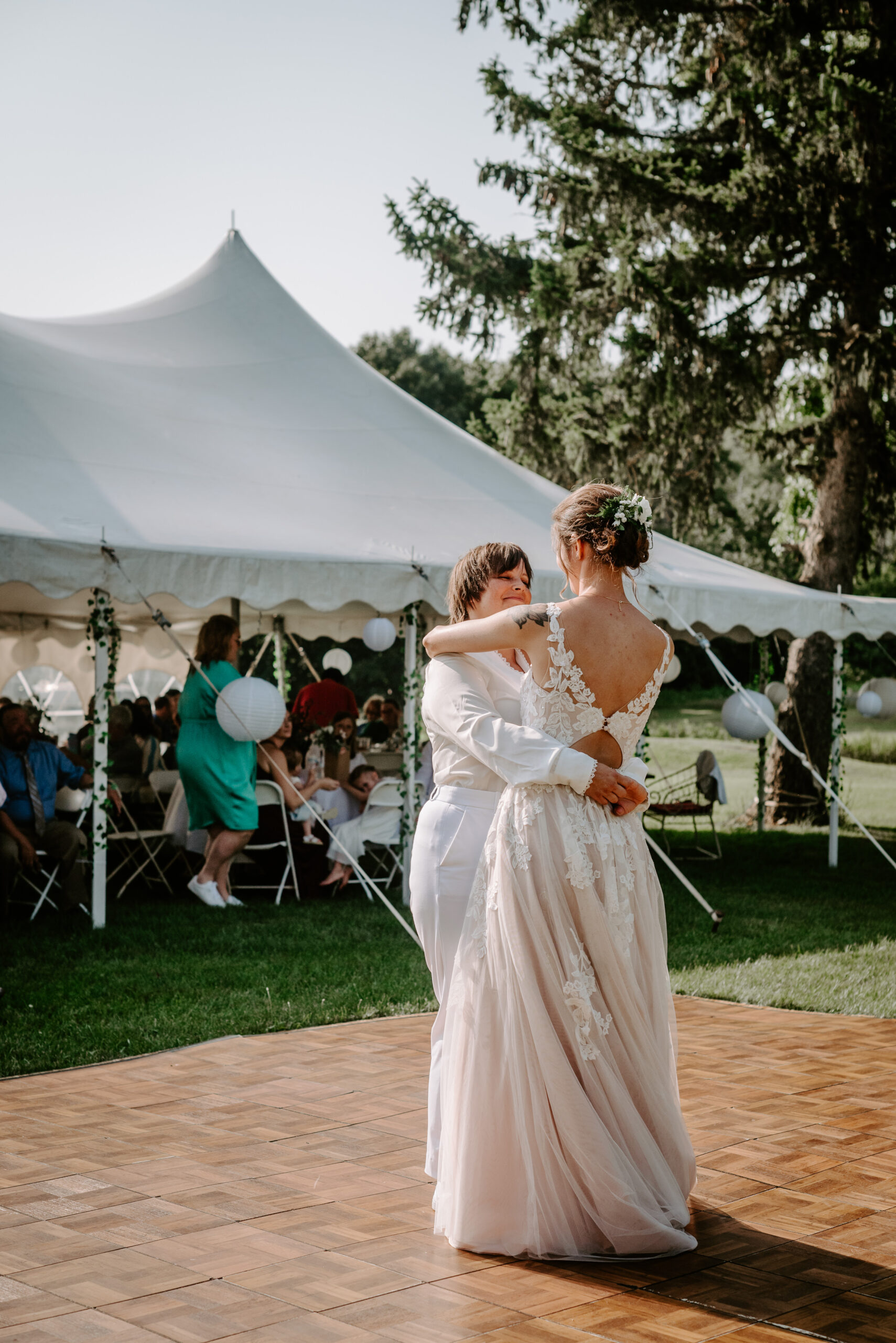 Two brides in Michigan during their tented reception wedding tent dance floor sharing first dance queer couple in Michigan LGBTQ plus wedding photographer near me