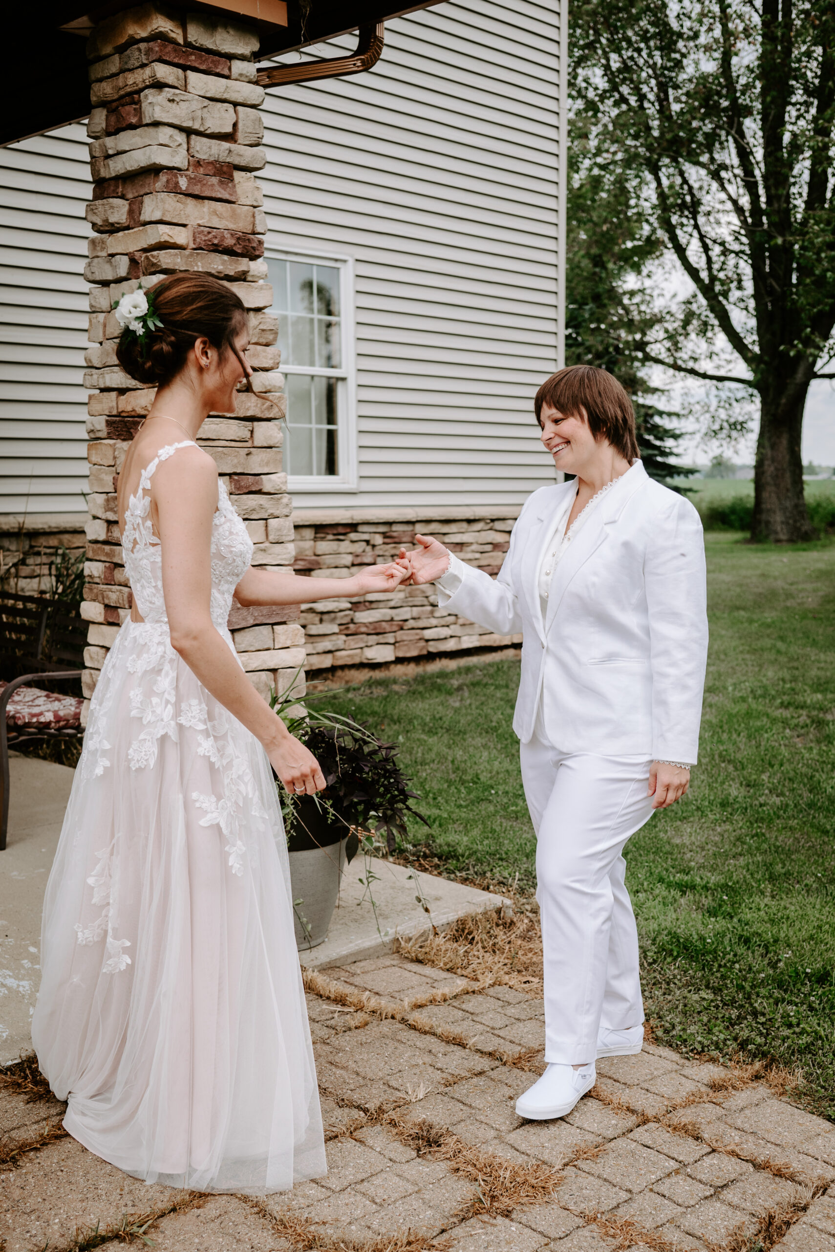two brides during first look, emotional first look with two women, queer brides, first look photo, queer bride in suit, queer bride in dress, backyard lgbtq wedding in Lawton Michigan