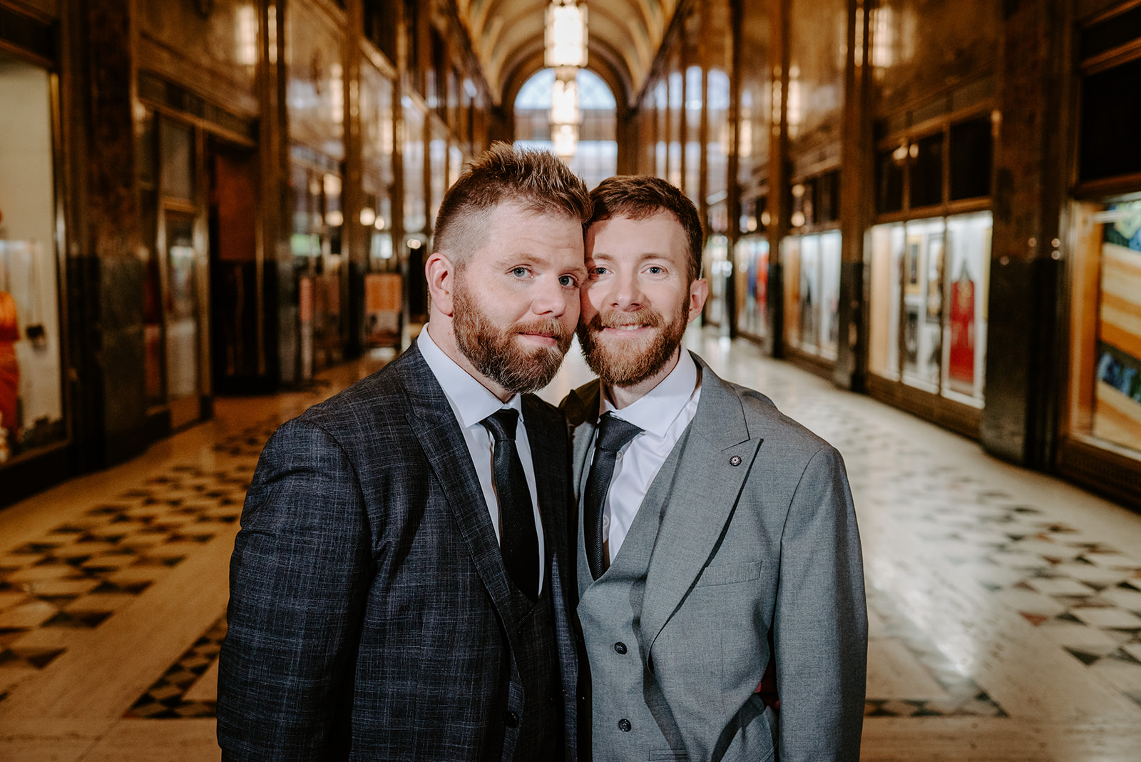 two gay men in gray and black suits on their wedding day having their photos taken at the historic fisher building in downtown detroit by Liv Lyszyk photography a queer and non binary wedding photographer from Grand Rapids Michigan