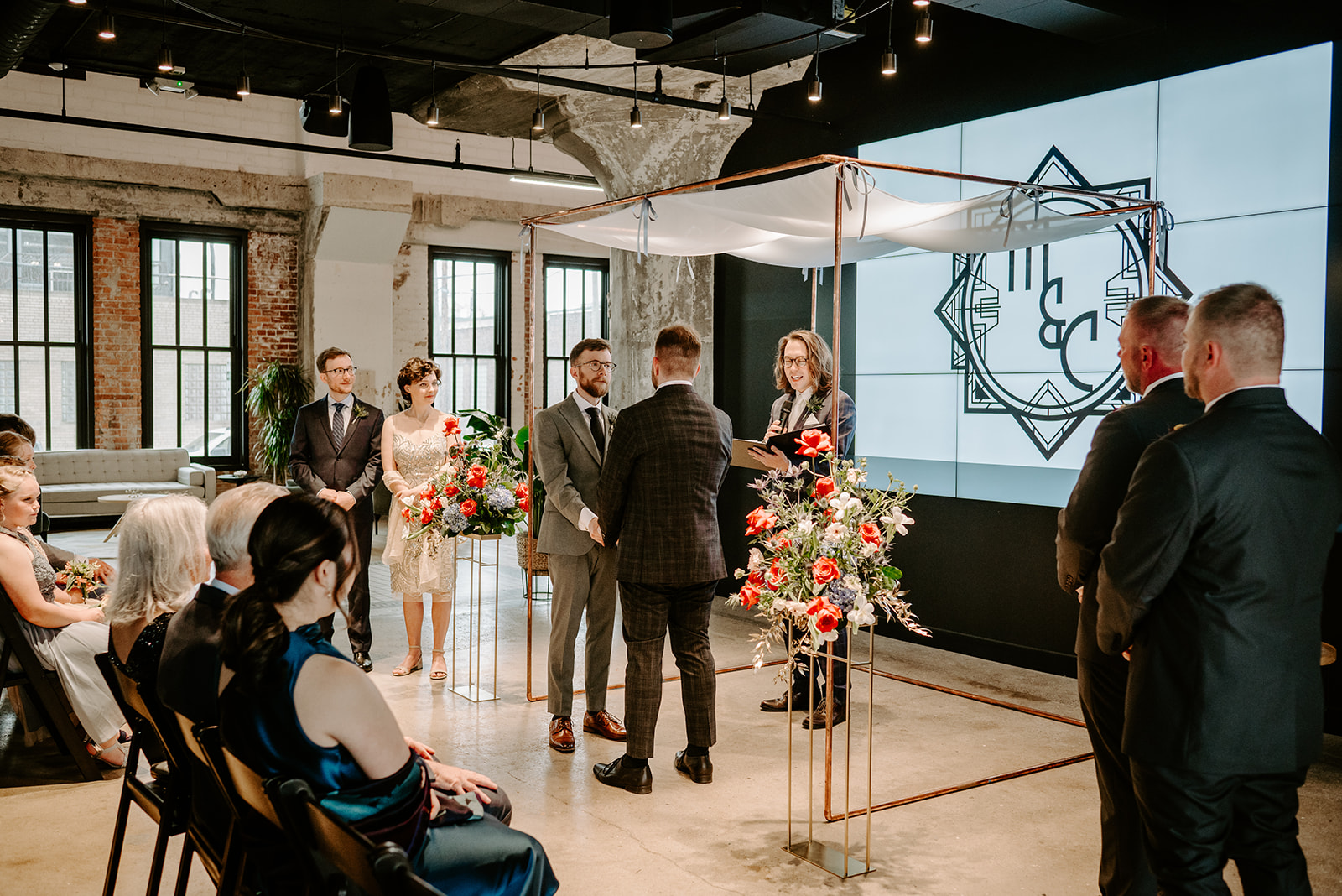 two gay men in gray and black suits at the altar at chroma detroit in michigan an elegant black tie wedding captured by Liv Lyszyk Photography a queer wedding photographer based out of Grand Rapids Michigan
