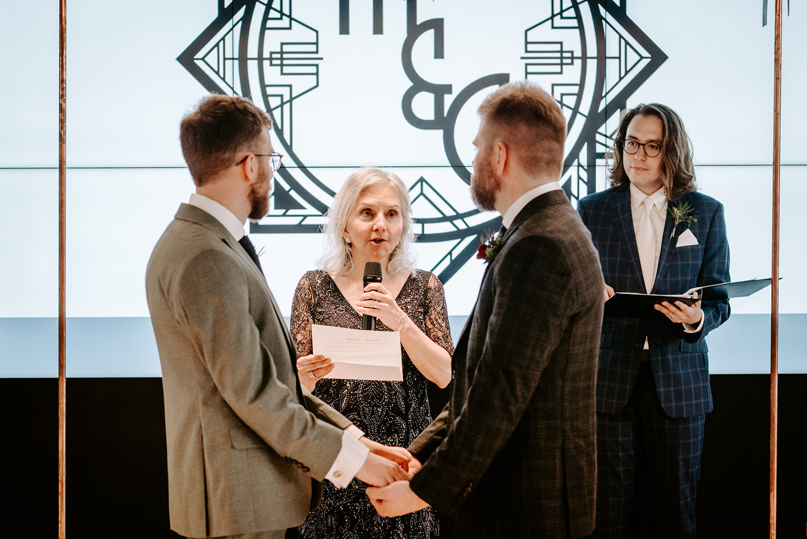 two gay men in gray and black suits at the altar at chroma detroit in michigan an elegant black tie wedding captured by Liv Lyszyk Photography a queer wedding photographer based out of Grand Rapids Michigan