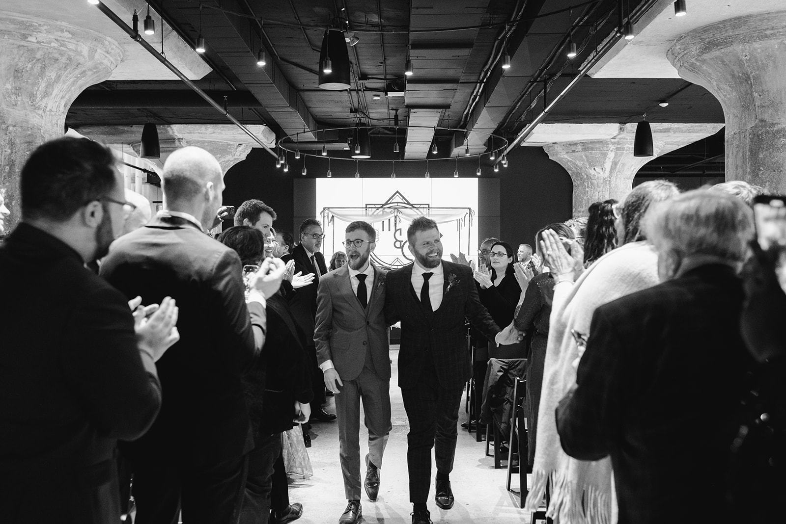 two gay men in gray and black suits at the altar at chroma detroit in michigan an elegant black tie wedding captured by Liv Lyszyk Photography a queer wedding photographer based out of Grand Rapids Michigan