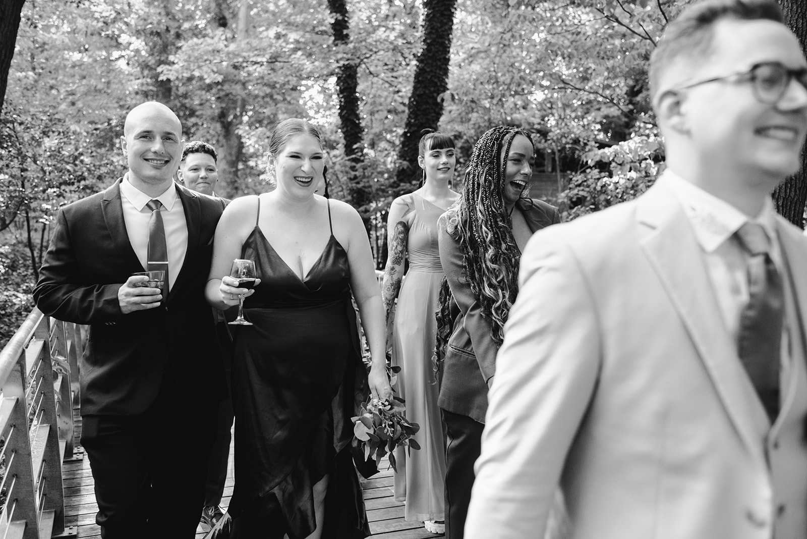 lgbt boho neutral wedding at john ball zoo in grand rapids michigan black and white photo of wedding party walking towards camera