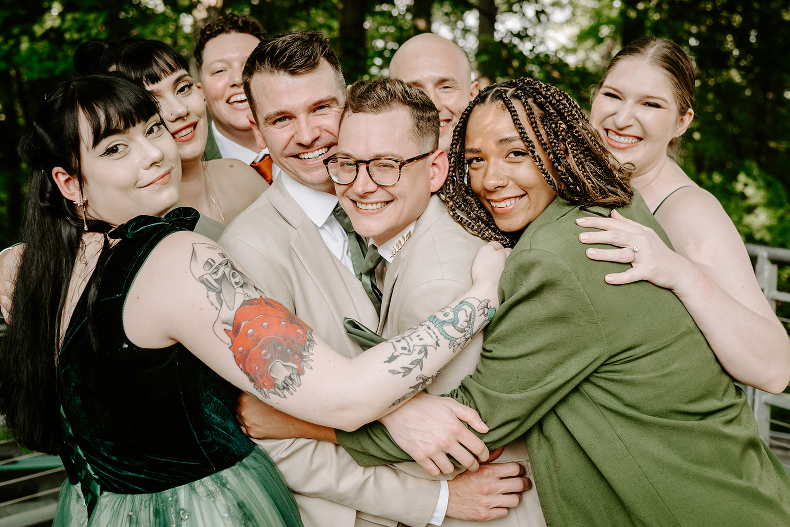 lgbt boho neutral wedding at john ball zoo in grand rapids michigan two grooms in tan suits with green accents being hugged by wedding party