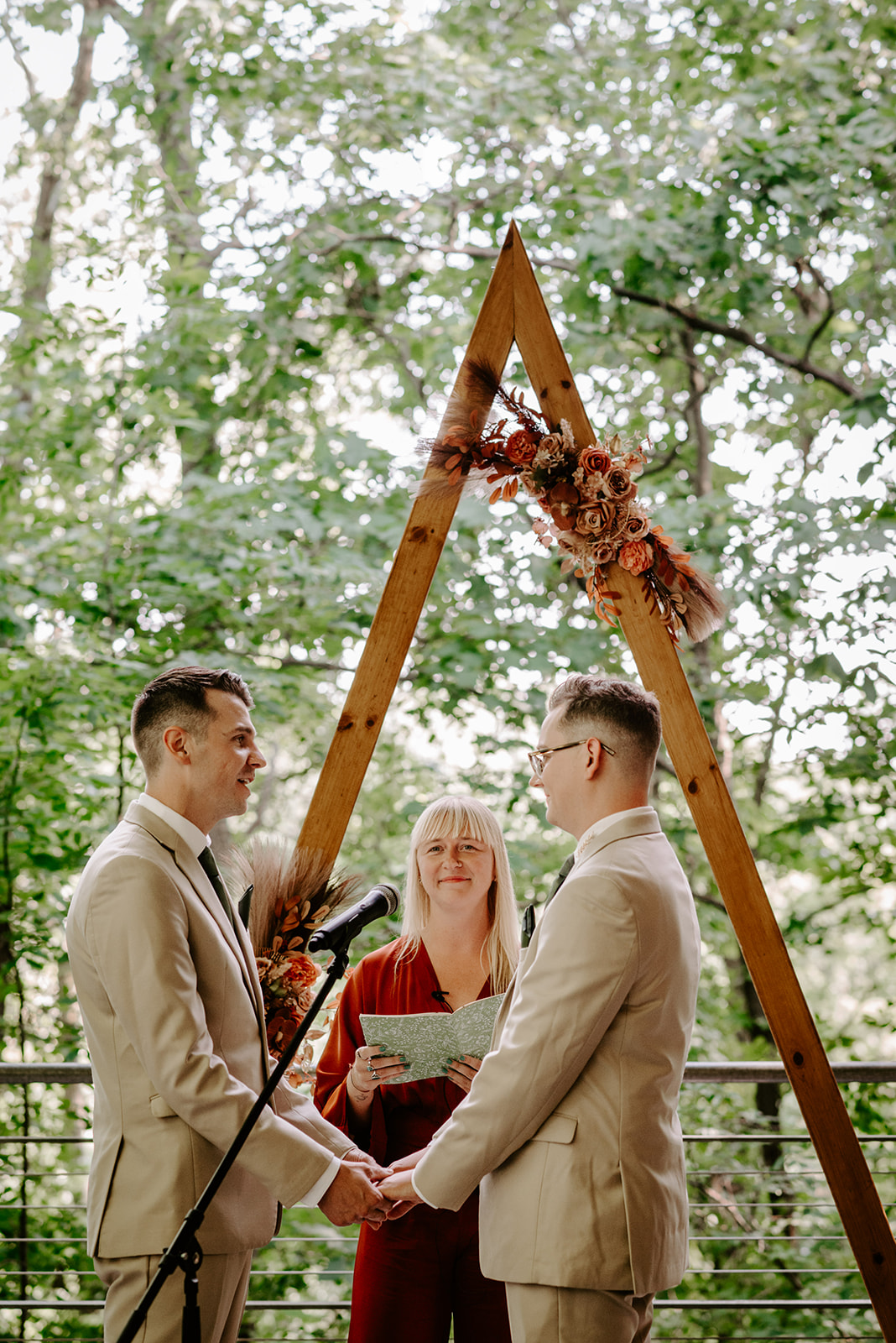 lgbt boho neutral wedding at john ball zoo in grand rapids michigan two grooms in tan suits with green accents with triangle arch saying I do