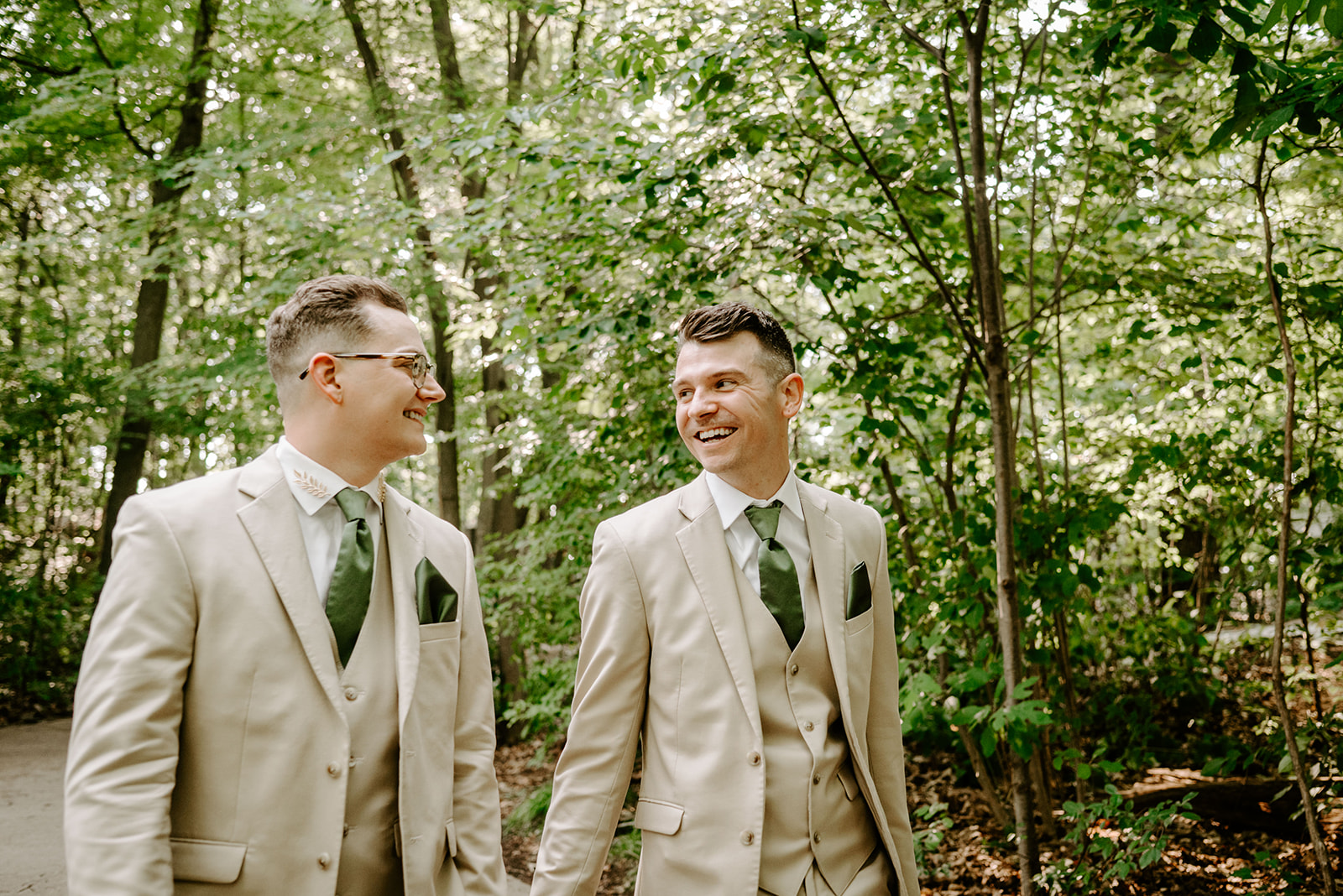 lgbt boho neutral wedding at john ball zoo in grand rapids michigan two grooms in tan suits with green accents walking and laughing