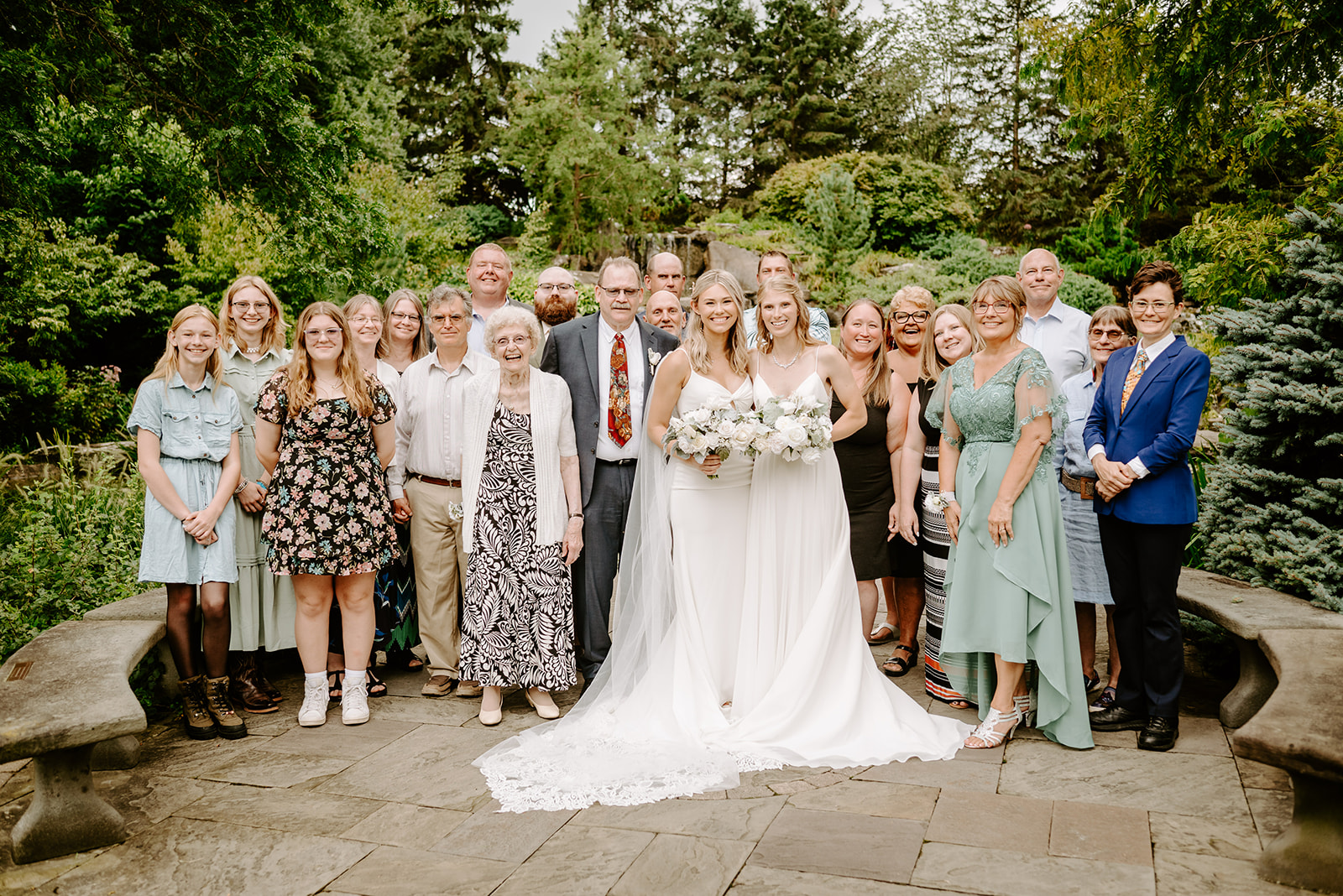 two brides getting married at Meijer gardens at a Grand Rapids LGBT Garden wedding with big group family photo right after wedding ceremony