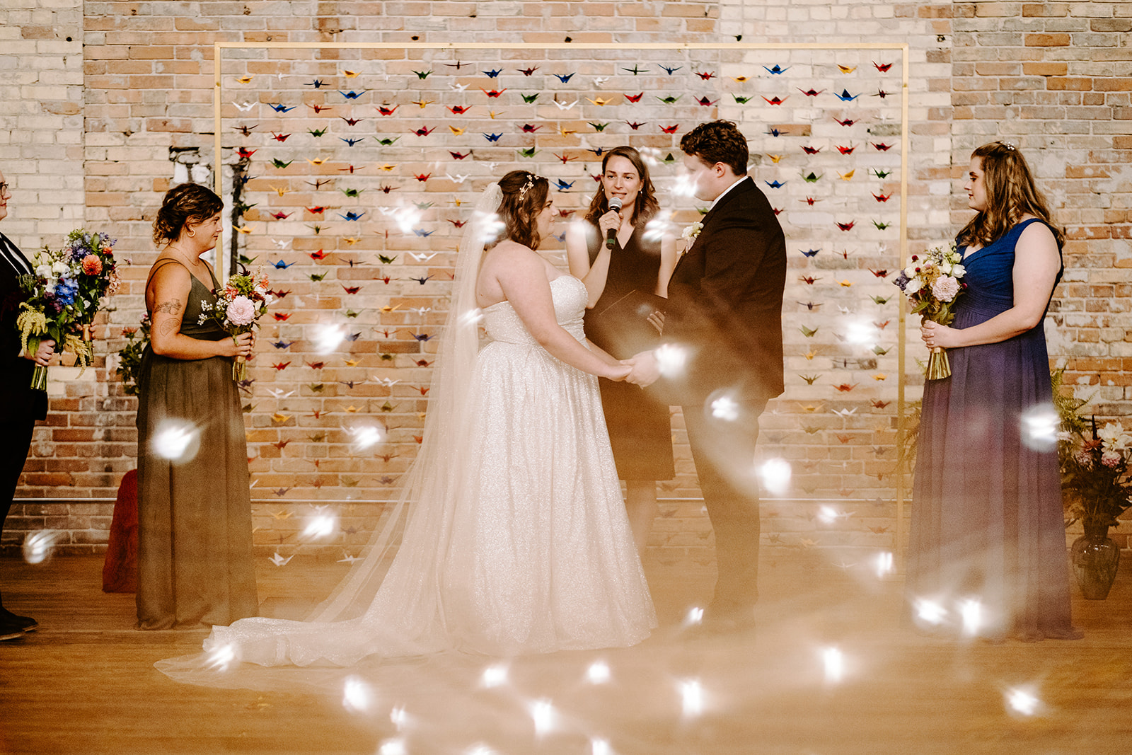 bride and groom with their officiant and attendants with blurred twinkle lights at a colorful downtown grand rapids michigan wedding 