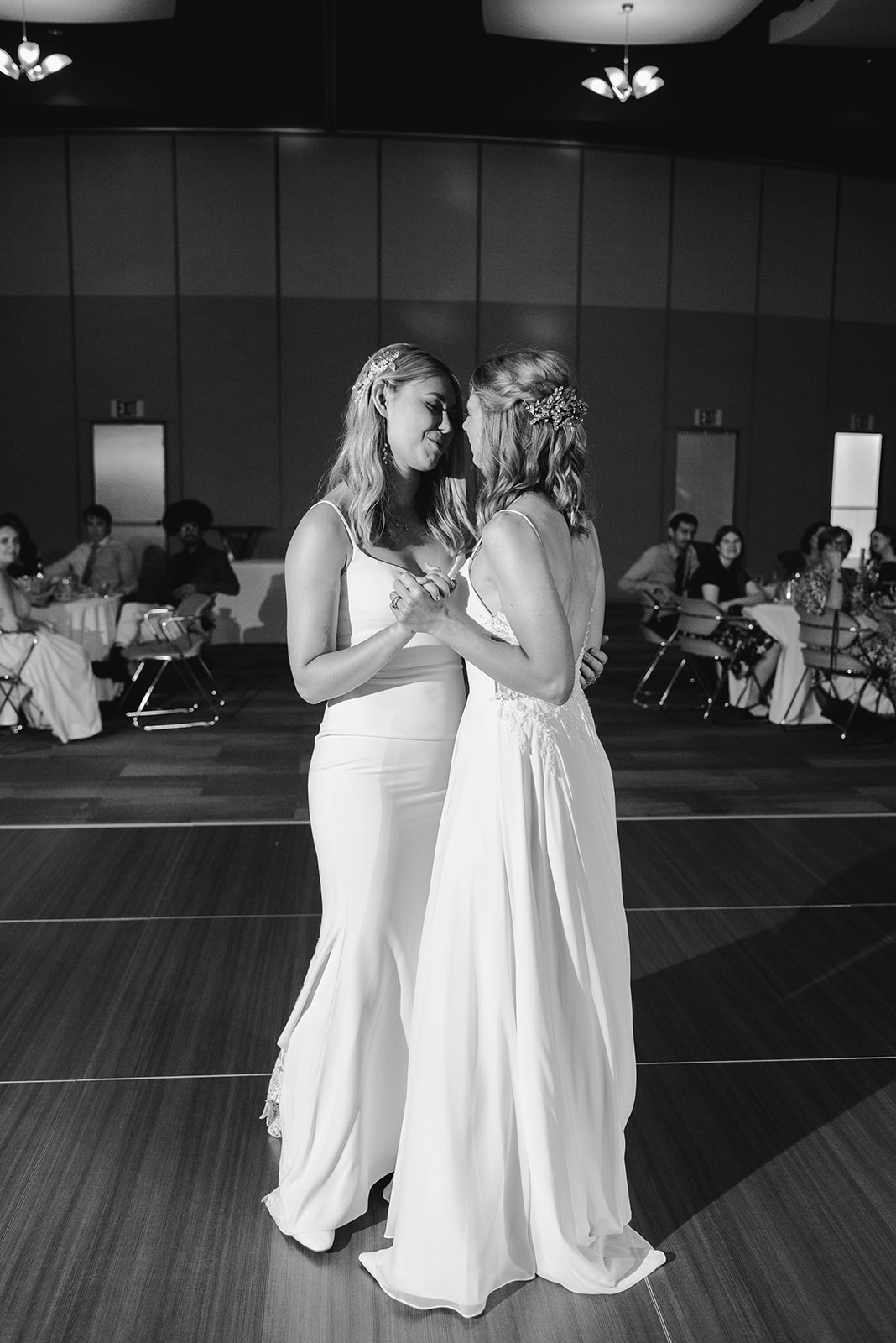 two brides getting married at Meijer gardens at a Grand Rapids LGBT Garden wedding enjoying their first dance in the grand ballroom in a black and white photo