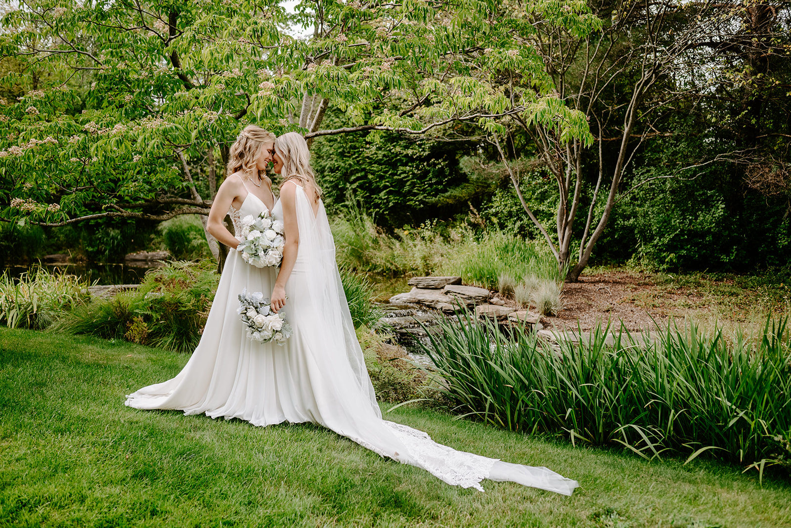 two brides getting married at Meijer gardens at a Grand Rapids LGBT Garden wedding during their emotional first look in the gardens near a pond