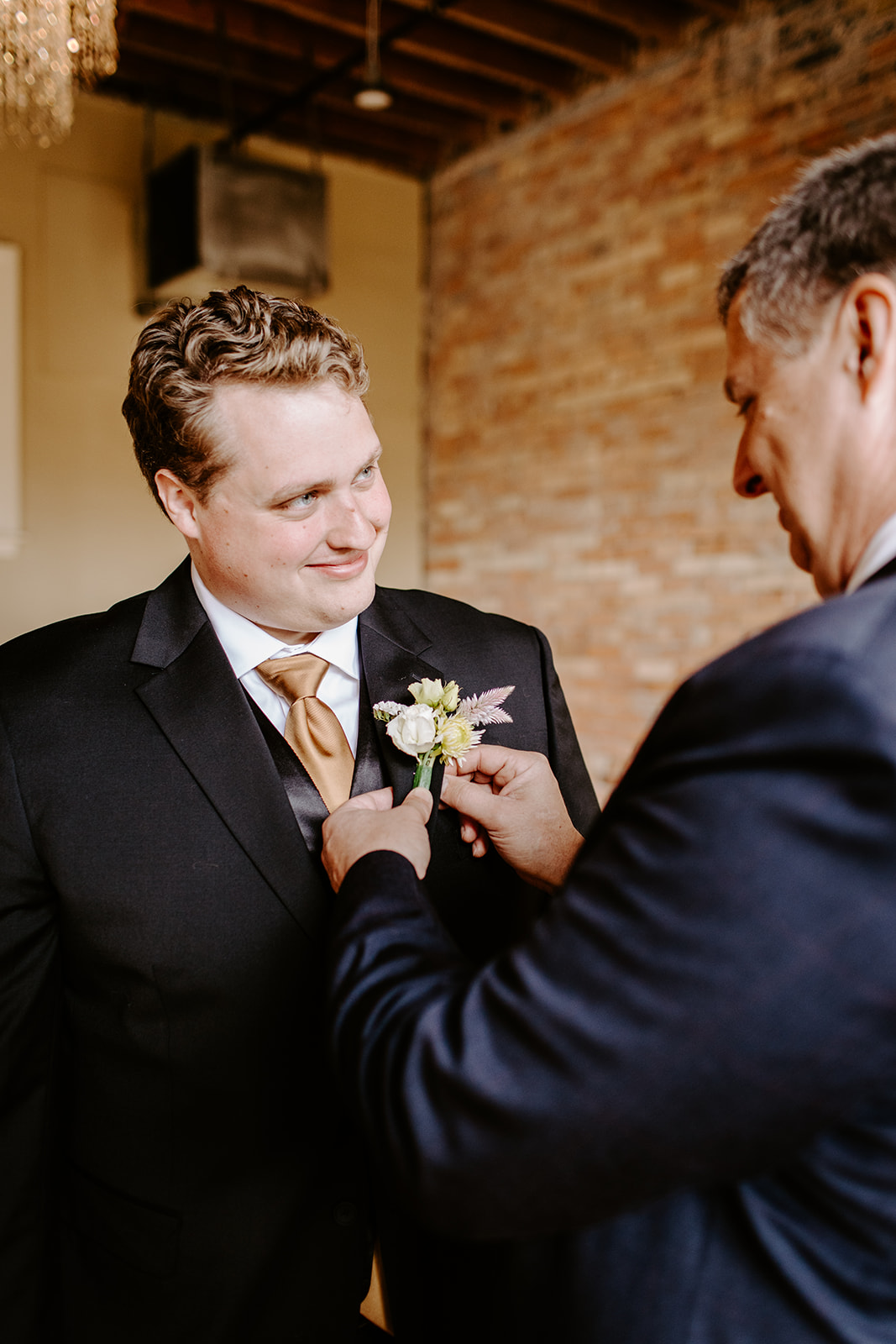 groom getting boutonniere pinned on by his dad at a colorful downtown grand rapids michigan wedding 