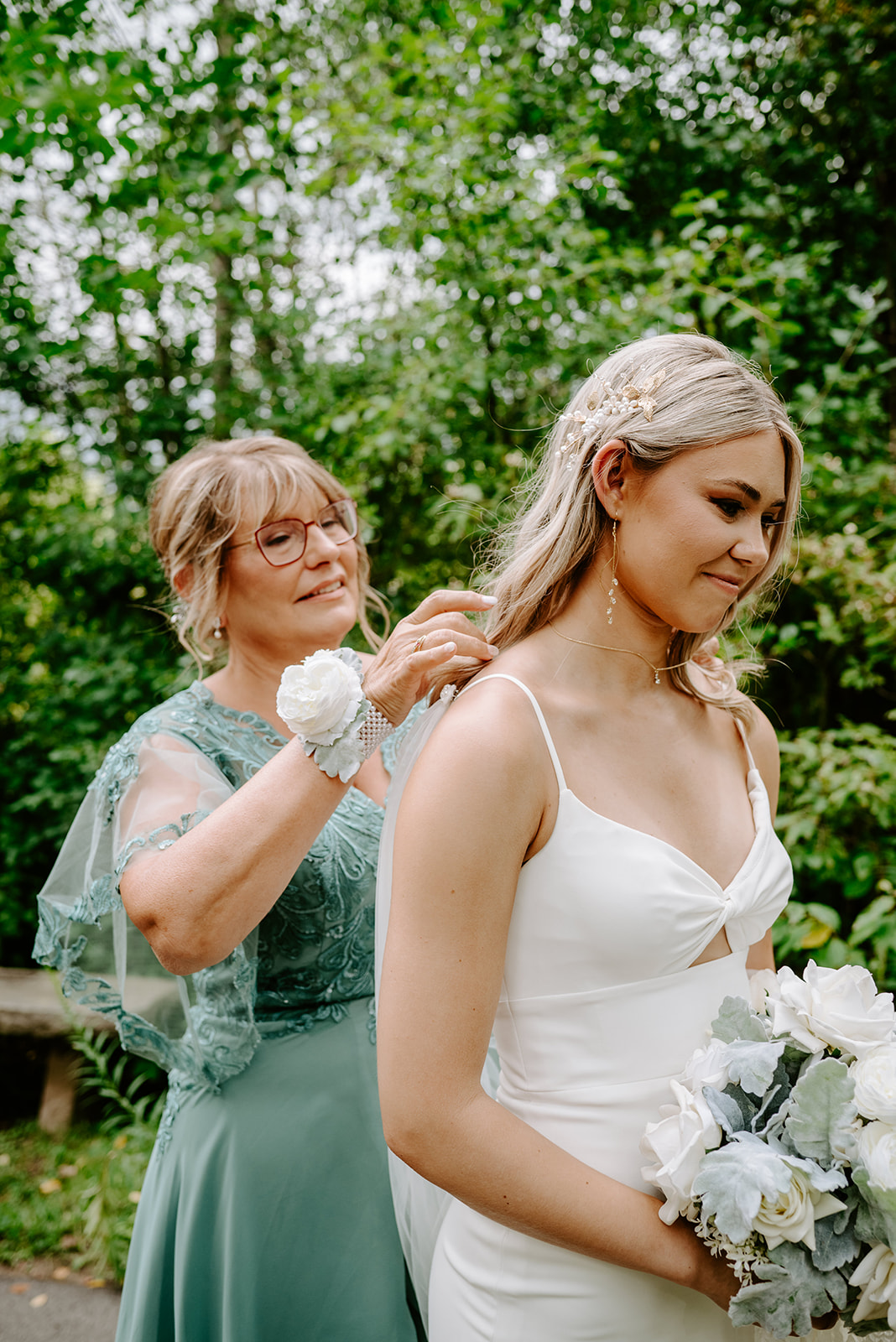 two brides getting married at Meijer gardens at a Grand Rapids LGBT Garden wedding with her mom putting on a necklace before the ceremony
