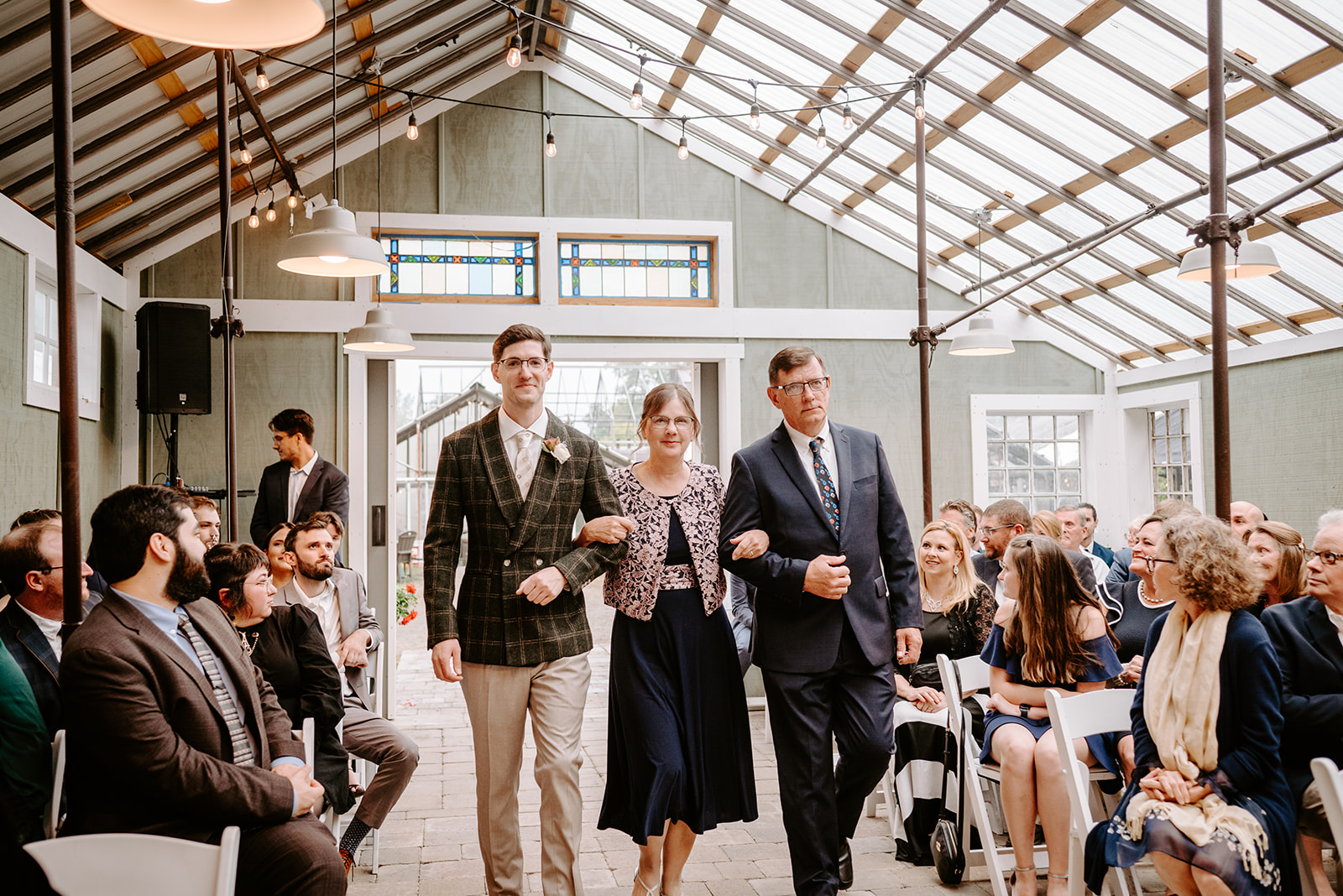 groom and parents walking down the aisle at greenhouse wedding at goldner walsh greenhouse in pontiac michigan by grand rapids and west michigan wedding photographer Liv Lyszyk Photography