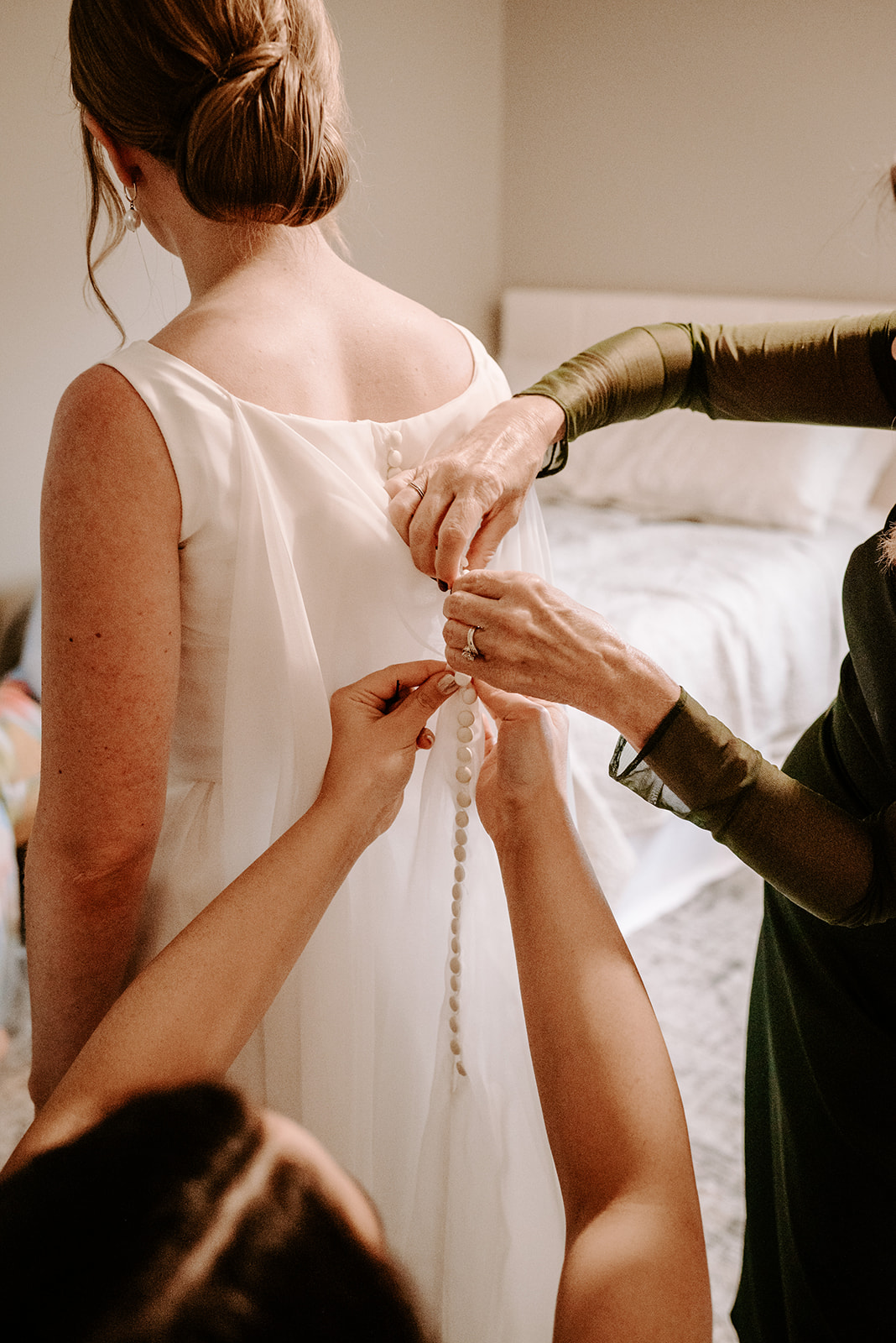 bride getting buttoned up at greenhouse wedding at goldner walsh greenhouse in pontiac michigan by grand rapids and west michigan wedding photographer Liv Lyszyk Photography