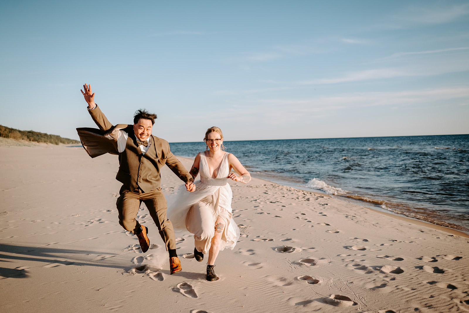 bride and groom running on beach at pj hoffmaster state park chinese american elopement photographed by Grand Rapids multicultural wedding photographer Liv Lyszyk Photographer
